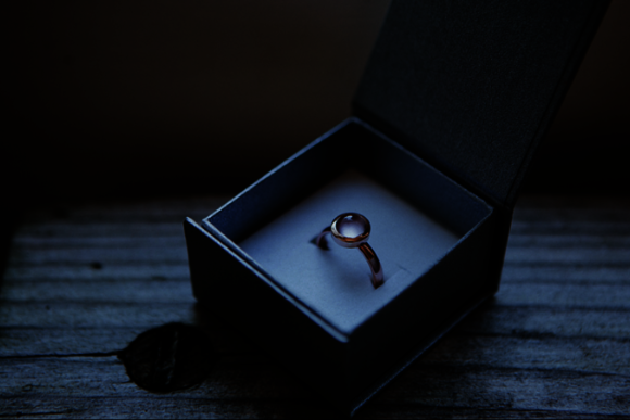 Ring mit Edelstein in einer Ringschatulle auf einem alten Holztisch 