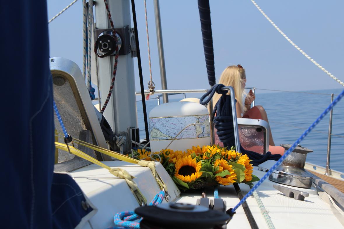 Urne auf Blumenschmuck mit blonder Dame auf einem Schiff im Meer