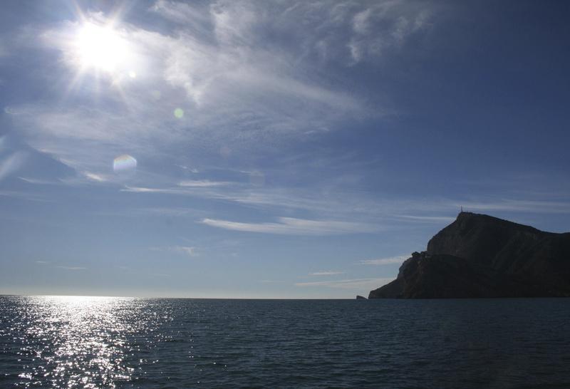 Bild vom Meer mit Sonneneinstrahlung und Küste im Hintergrund